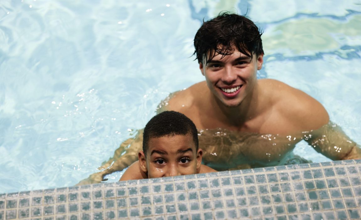 Young student with swim instructor in a swimming pool.