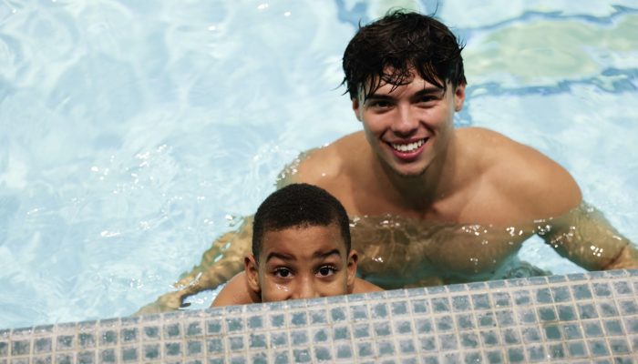 Young student with swim instructor in a swimming pool.