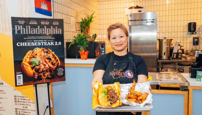Pidor Yang, owner of Sahbyy Food, stands in front of her business' booth at Gather Food All in University City. She is holding a tray with food on it, including Sahbyy Food's signature Cambodian lemongrass cheesesteak.