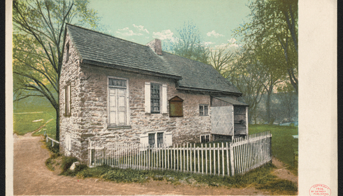 A color postcard, dated 1905, showing a stone building with a small white picket fence.