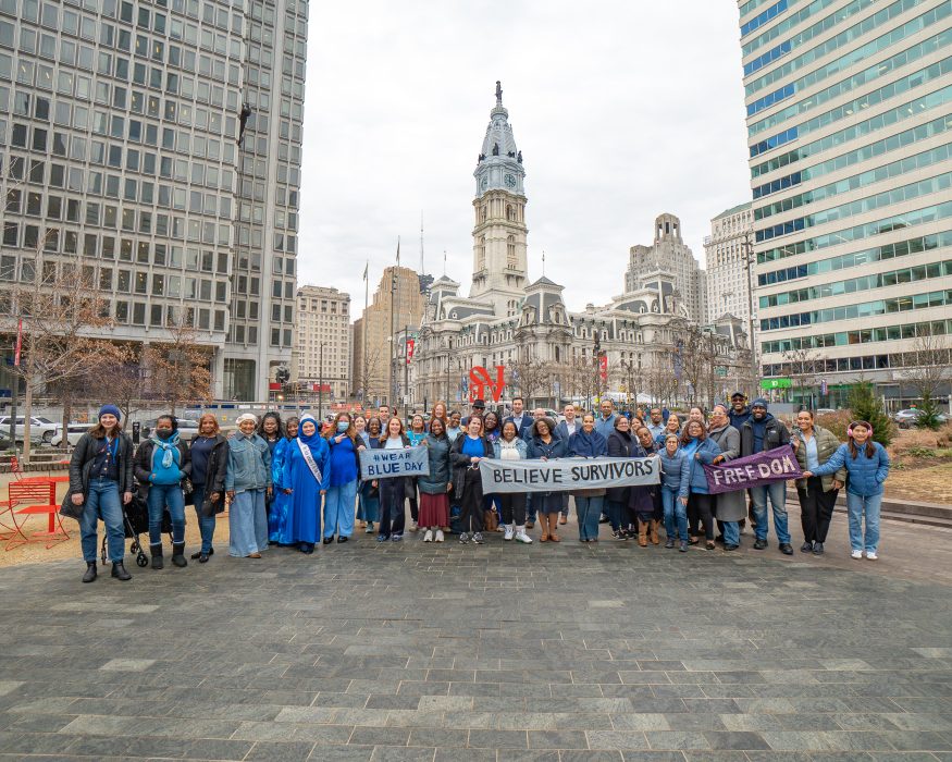 A group of advocates wearing blue stand in Love Park holding banners that say "Believe Survivors," "Wear Blue Day" and "Freedom" for Human Trafficking Awareness Day