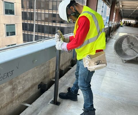 Construction worker in yellow vest and hard hat holding iron bar