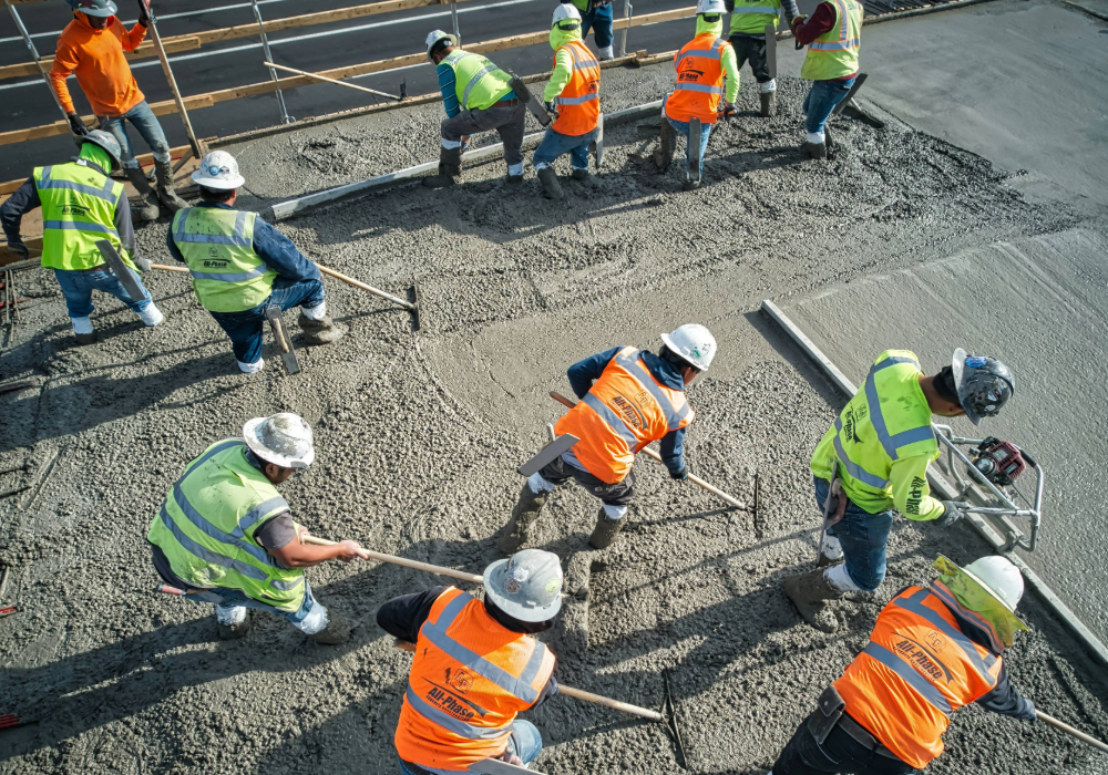 Construction workers smoothing and leveling concrete at an elevated level of a new apartment building complex development.