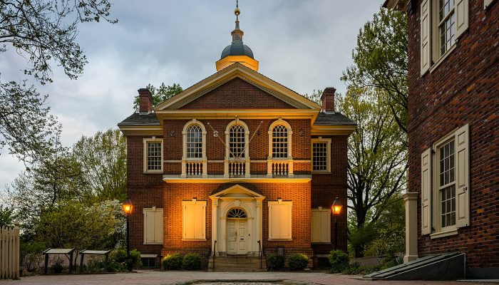 A Colonial-era brick building with a weathervane on top.