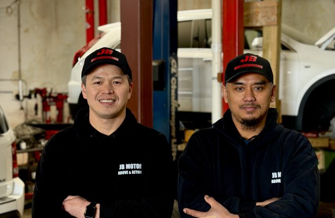 JB Motor Works’ co-founder, John Lin and his business partner Bruce together at the business with a car on a lift in the background.