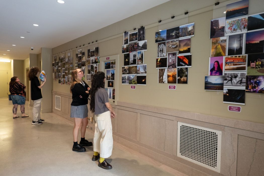 Two young people look at a wall of photographs.