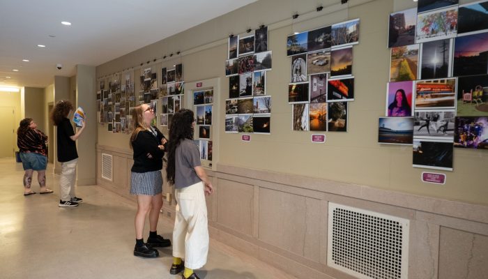 Two young people look at a wall of photographs.
