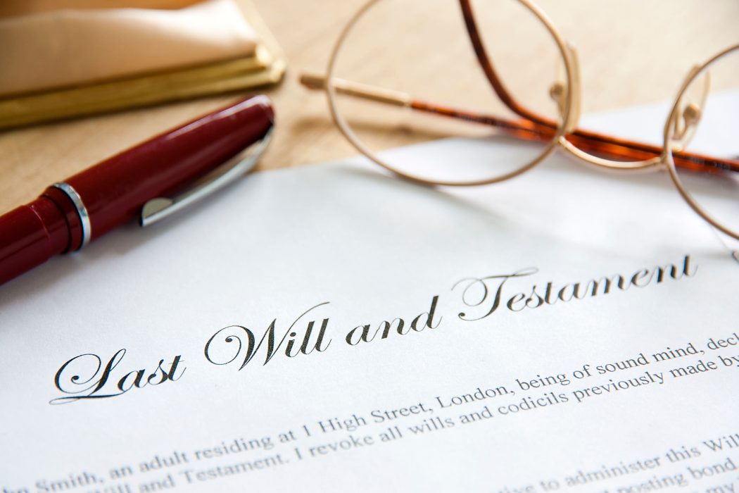 A paper reading Last Will and Testament with a pen on the left and glasses to the right