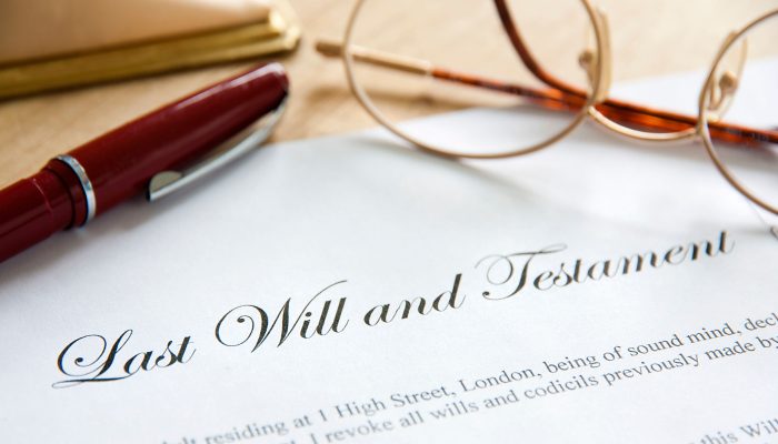 A paper reading Last Will and Testament with a pen on the left and glasses to the right
