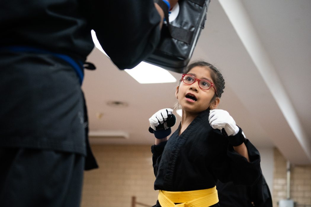 A young woman in a self-defense stance with her hands raised.