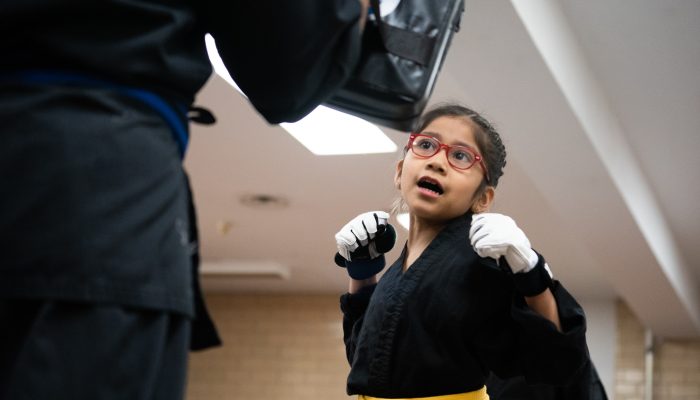 A young woman in a self-defense stance with her hands raised.