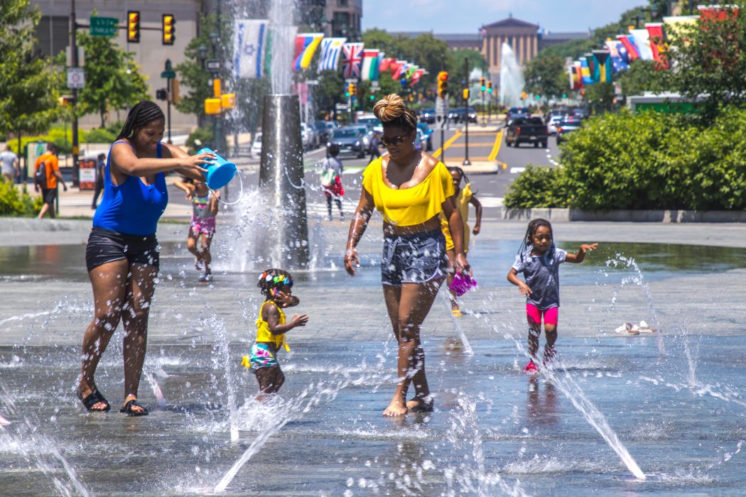 Two women and two children play in the fountain at LOVE Park in the summertime