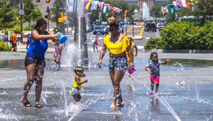 Two women and two children play in the fountain at LOVE Park in the summertime