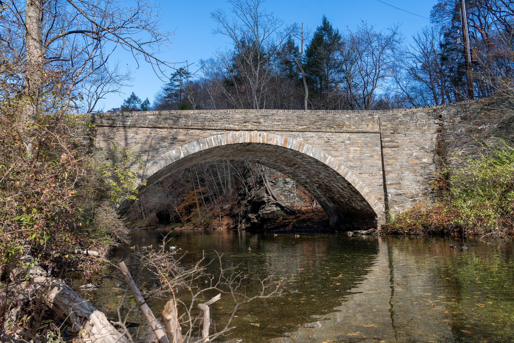 A side view of the bridge’s single stone arch across Wissahickon Creek.