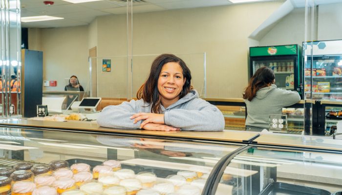 Business owner stands behind a case of pastries at Denise's Delicacies in North Philadelphia