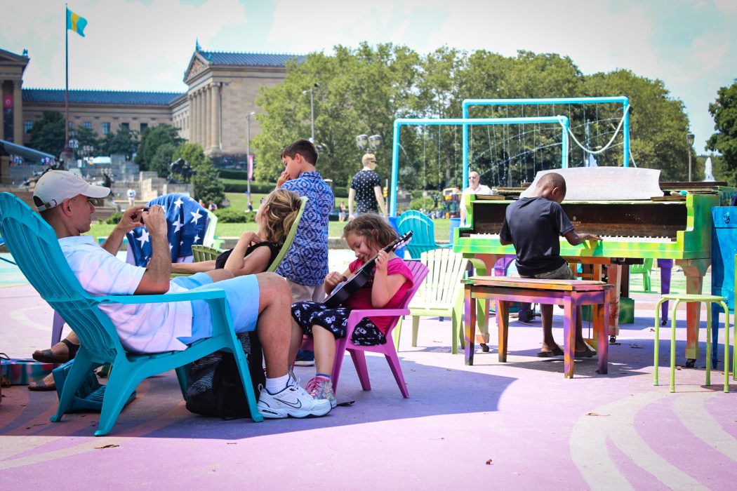 A group of people gather together playing instruments and games at The Oval.