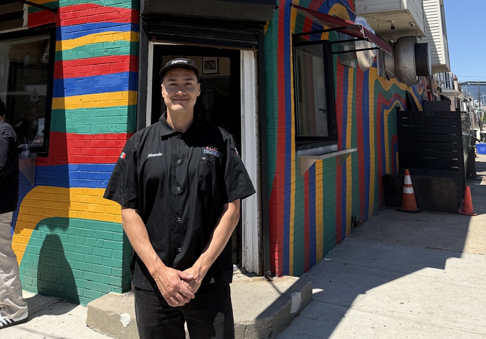 Business owner standing in front of Korea Taqueria with colorfully painted business in background