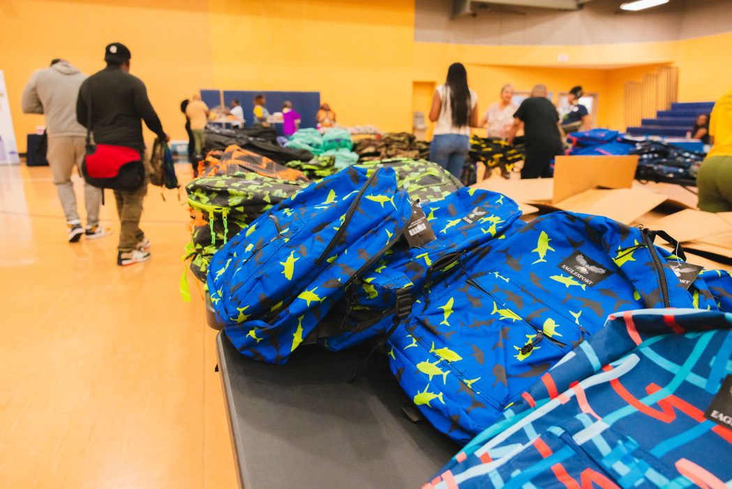 Bright blue backpacks on a table at a backpack give away event.