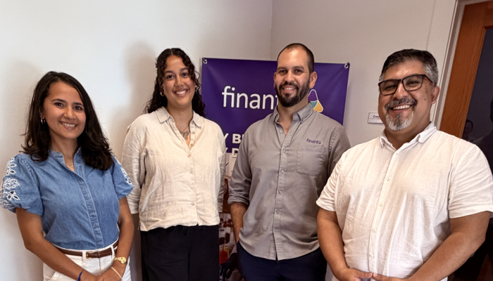 PBLN lender Giovannie Vilomar, microloan business consulting manager at Finanta, smiles along with other members of the Finanta lending team in front of a Finanta banner