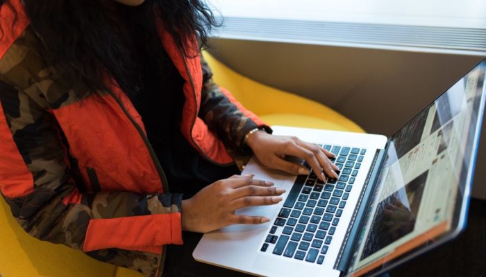 Woman in a red puffy jacket browses the web on a laptop