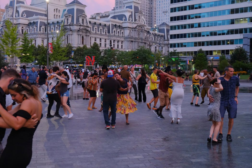 A group of people dance in pairs to lively music in Love Park.
