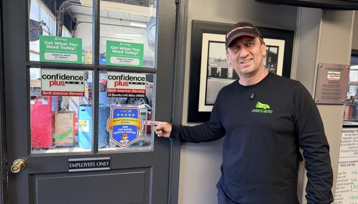  Richard Sanchez stands in front of a door with stickers on it at Dave's Automotive in Tacony.